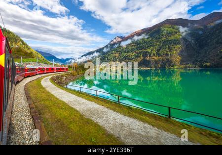 Roter Zug auf der Bernina Express Route entlang des Miralago Sees in den Schweizer Alpen, Val Poschiavo im Kanton Graubünden, Schweiz. Stockfoto