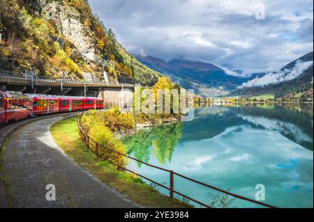 Roter Zug auf der Bernina Express Route entlang des Miralago Sees in den Schweizer Alpen, Val Poschiavo im Kanton Graubünden, Schweiz. Stockfoto