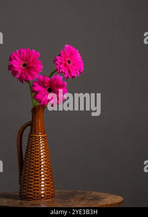 Minimalistische Einrichtung, Blumenstrauß von Gerbera in Vase auf rundem Tisch. Stockfoto