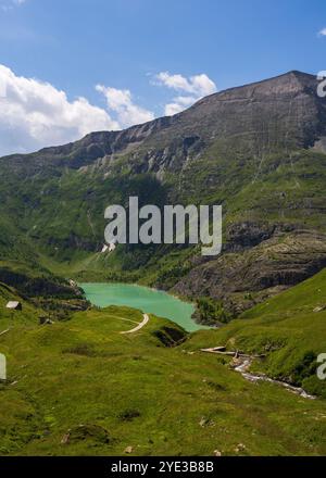 Kleiner blauer See zwischen Berghängen. Kleines Hotel in den Bergen, Hütte für Touristen. Großglockner Hochalpenstraße, Österreich. Großglockner Hochalpin Stockfoto