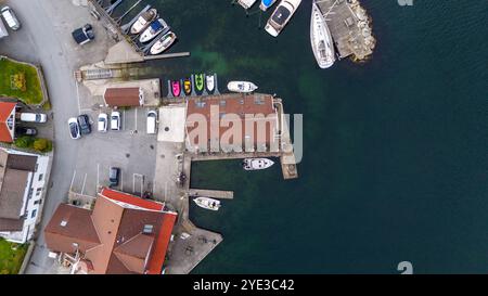 Blick aus der Vogelperspektive auf einen Yachthafen mit Booten, die entlang des Piers angedockt sind, umgeben von Gebäuden und geparkten Autos. Stockfoto