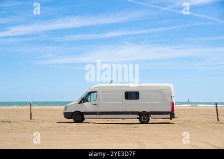 Alter weißer Wohnwagen, der an einem Strand am Meer im Ebro-Delta, Spanien, geparkt wurde. Nomadisches und freies Leben. Stockfoto