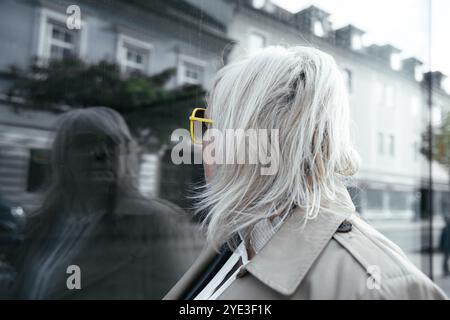 Eine lächelnde Frau mittleren Alters, die eine Brille trägt, läuft durch die Stadt Stockfoto