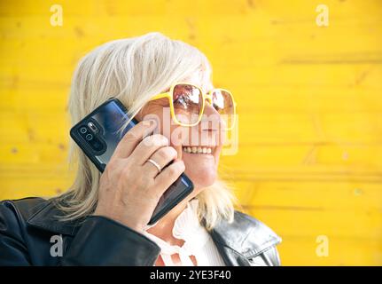 Eine lächelnde Frau mittleren Alters, die eine Brille trägt, läuft durch die Stadt Stockfoto