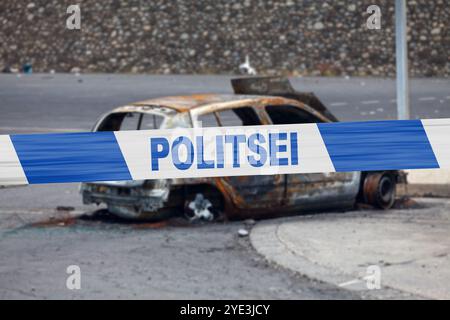 Auto verbrannt von einem Pyromanen mit einem Polizeiband, in dem auf Estnisch "POLITSEI" geschrieben ist. Stockfoto