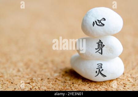 Text für Geist, Körper und Geist in chinesischer Schrift auf weißen Steinen. Meditation und Friedenskonzept. Stockfoto