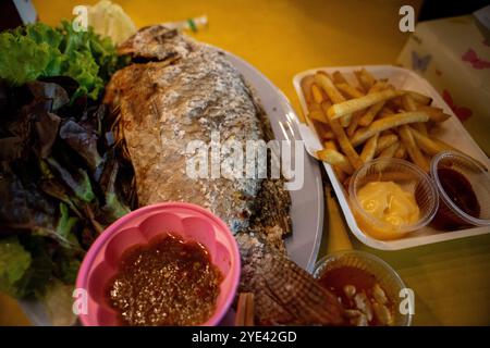 Gegrillter Tilapia mit Salzkruste und Pommes Frites und Dip Soßen auf dem Chiang Rai Nachtmarkt. Stockfoto