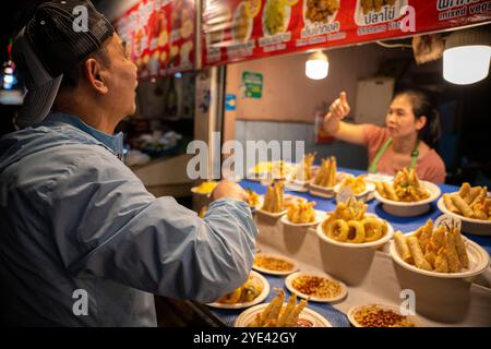 Ein Tourist wählt Street Food mit Anleitung von einem Händler auf dem Chiang Rai Nachtmarkt in Thailand aus. Stockfoto