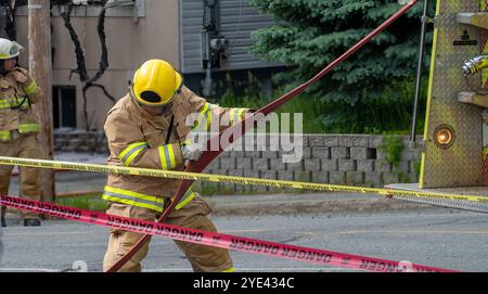 Der Feuerwehrmann zieht einen roten Feuerwehrschlauch aus einem Feuerwehrauto Stockfoto