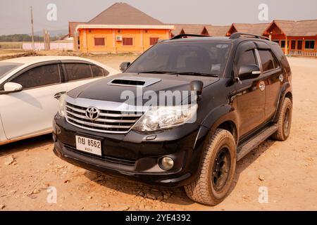 Ein Toyota Fortuner mit thailändischen Platten, der durch die malerische Landschaft von Laos fährt. Stockfoto