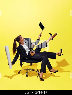 Kreative Collage. Geschäftsfrau mit mehreren Händen und Beinen, die im Bürostuhl sitzt und geschickt mit verschiedenen Büromaterialien wie Laptop, Becher jongliert Stockfoto