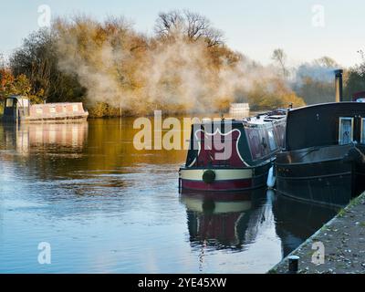 Hausboote, die auf der Themse am Abingdon Lock vertäut sind. Abingdon-on-Thames behauptet, die älteste Stadt Englands zu sein. Und die Themse fließt durch ihr Herz. In dieser idyllischen Szene sehen wir einen erholsamen Blick auf den Fluss vom Abingdon Weir, an einem nebeligen, stimmungsvollen Morgen, gerade kalt genug für die Boote, um ihre Heizkessel anzuzünden Stockfoto