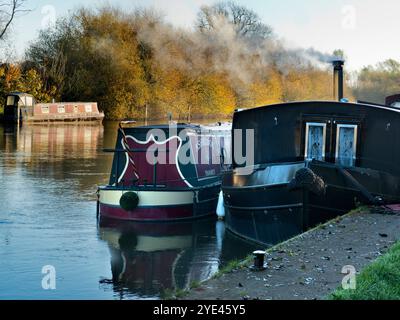 Hausboote, die auf der Themse am Abingdon Lock vertäut sind. Abingdon-on-Thames behauptet, die älteste Stadt Englands zu sein. Und die Themse fließt durch ihr Herz. In dieser idyllischen Szene sehen wir einen erholsamen Blick auf den Fluss vom Abingdon Weir, an einem nebeligen, stimmungsvollen Morgen, gerade kalt genug für die Boote, um ihre Heizkessel anzuzünden Stockfoto