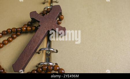 Dunkelrotes Holzkreuz, das sich an ein altes offenes Buch lehnt, das die Verbreitung der Liebe Jesu Christi unter Christen symbolisiert, die den Glauben und die Hingabe widerspiegelt Stockfoto