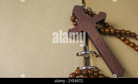 Dunkelrotes Holzkreuz, das sich an ein altes offenes Buch lehnt, das die Verbreitung der Liebe Jesu Christi unter Christen symbolisiert, die den Glauben und die Hingabe widerspiegelt Stockfoto