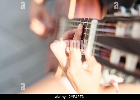 Nahaufnahme einer Frauenhand, die Gitarre spielt. Ihre Hand macht einen Akkord. Stockfoto