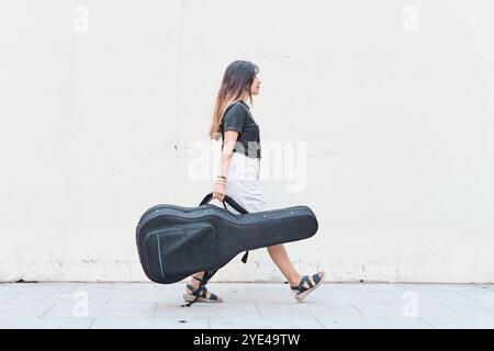 Kaukasierin mit Gitarrenkoffer auf dem Bürgersteig Stockfoto