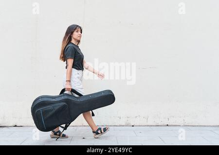 Kaukasierin mit Gitarrenkoffer auf dem Bürgersteig Stockfoto