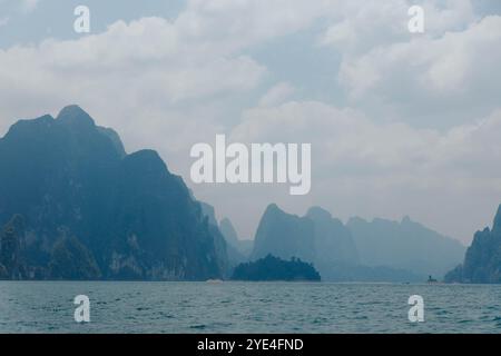 Die Landschaft zeigt majestätische Berge mit einer ruhigen Bucht im Vordergrund. Nebelwolken erheben sich über den Gipfeln und tragen zur friedlichen Atmosphäre von bei Stockfoto