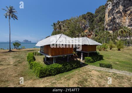 Zwei charmante Villen am Strand, umgeben von lebhaftem Grün, stehen vor einem Hintergrund von Klippen und einem klaren blauen Himmel, die Entspannung am Meer bieten. Stockfoto