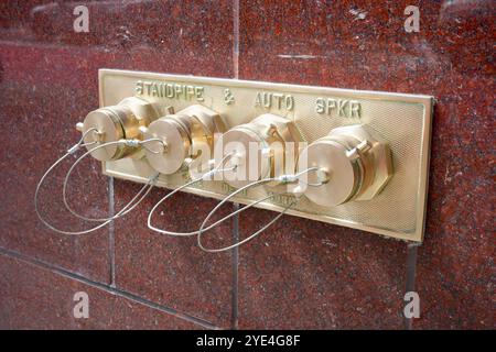 Messing-Standrohr und automatische Sprinkleranlage an einer Wand aus rotem Granit. Stockfoto