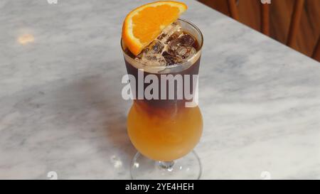 Erfrischender Eiskaffee mit Orangenscheibe auf Marmortisch, modern Stockfoto