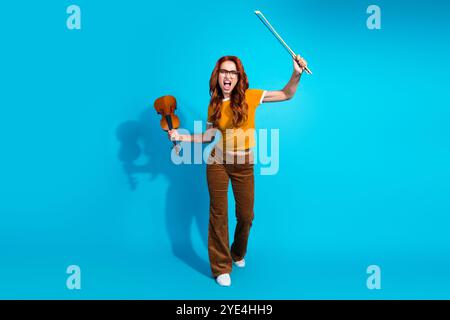 Foto einer wütenden jungen Musikerin tragen trendige Kleidung halten Violine isoliert auf blauem Hintergrund Stockfoto