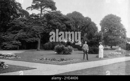 West Sussex, England. 1913 – Ein junger Mann und eine ältere Frau, die vermutlich Mitglieder der Familie Henty sind, befinden sich auf dem Gelände von Ferring Grange in Ferring, einem Küstendorf in West Sussex. Das Anwesen war das Zuhause von Edwin Henty, J. P, D.L., F.S.A. (1844–1916), der als High Sheriff of Sussex gedient hatte. 1924 wurde das Haus in ein modisches Hotel umgewandelt, das von vielen Prominenten besucht wurde, darunter Edward, dem Prinzen von Wales (später bekannt als Duke of Windsor). Das Haus wurde im Oktober 1946 durch einen Brand zerstört. Stockfoto