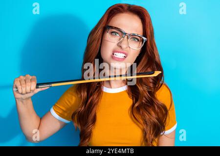 Foto einer verrückten jungen Musikerin tragen trendige Kleidung halten Geigenbogen isoliert auf blauem Hintergrund Stockfoto