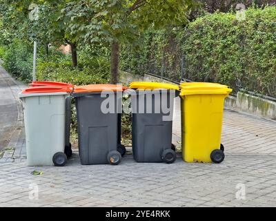 Vier Abfallbehälter stehen auf dem Bürgersteig. Die Mülleimer haben verschiedene Farben und Größen Stockfoto
