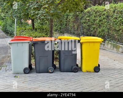 Vier Abfallbehälter stehen auf dem Bürgersteig. Die Mülleimer haben verschiedene Farben und Größen Stockfoto