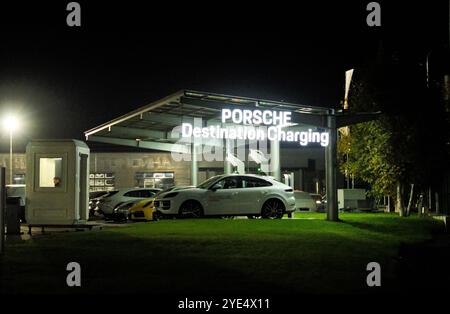 Almaty, Kasachstan - 18. Oktober 2024: Elektrische Porsche-Autos parken nachts an einer Ladestation. Händlerbetrieb Stockfoto