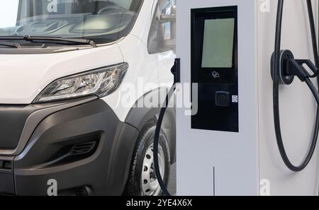 Elektrische Lieferwagen mit Ladestation für Elektrofahrzeuge. Stockfoto