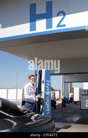 Der Mann hält eine Wasserstoffdüse an einer Wasserstofftankstelle. Betanken des Autos mit Wasserstoffkraftstoff. Stockfoto