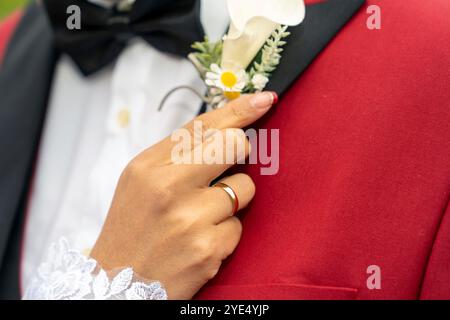 Die Hand der Braut platziert die Blume des Bräutigams Stockfoto