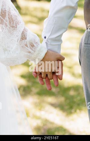 Romantische, miteinander verflochtene Hände einer Braut und eines Bräutigams in einer Outdoor-Umgebung. Stockfoto