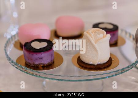 Elegante Präsentation von Gourmet-Desserts in Herzform auf einem Glaskuchenständer. Stockfoto