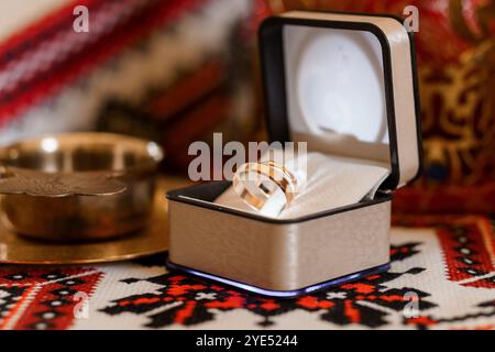 Elegante goldene Hochzeitsringe in einer luxuriösen Box auf textilem Hintergrund. Stockfoto