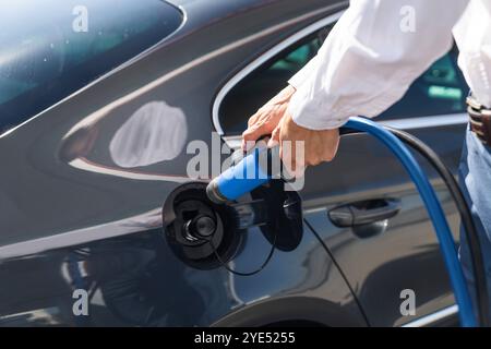 Der Mann hält eine Wasserstoffdüse an einer Wasserstofftankstelle. Betanken des Autos mit Wasserstoffkraftstoff. Stockfoto