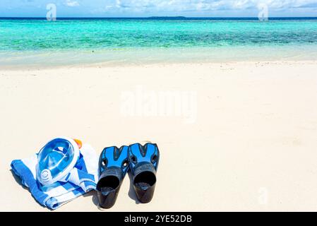 Flossen, ein Handtuch und eine Unterwassermaske auf dem Sand am Ufer des Indischen Ozeans. Malediven-Inseln. Stockfoto