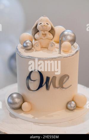 Eleganter Kuchen zum ersten Geburtstag mit Häschen-Topper. Stockfoto