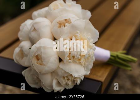 Eleganter weißer Pfingstrosen-Brautstrauß auf Holzbank. Stockfoto