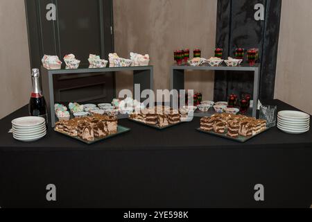 Elegantes Desserttablett mit Kuchen, Cupcakes und Champagner. Stockfoto