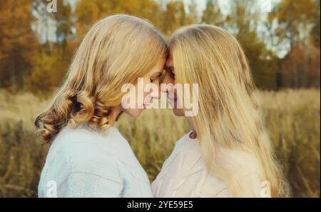 Porträt von glücklichen zwei Frauen, lächelnder reifer Mutter und erwachsener Tochter, die sich im Herbstpark umarmt Stockfoto