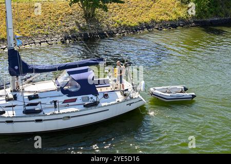 Veere, Zeeland, Niederlande - 10. August 2022: Person, die eine Yacht mit einem Schlauchboot in Richtung der Stadt Veere lenkt. Stockfoto