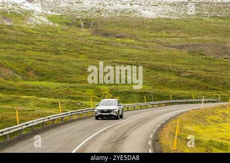 Akureyri, Island - 24. August 2024: Auto fährt auf einer der kurvenreichen Straßen über Berge in den abgelegenen Gebieten des Nordens Islands. Stockfoto