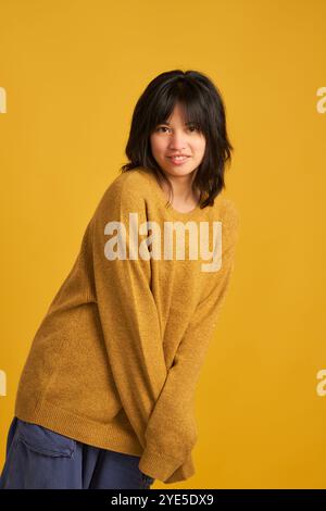 Eine Frau in einem gelben Pullover posiert für ein Foto. Sie hat kurze Haare und lächelt Stockfoto