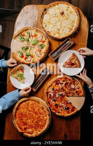 Auswahl an köstlichen Pizzen auf einem rustikalen Tisch, perfekt für ein zwangloses Essen Stockfoto
