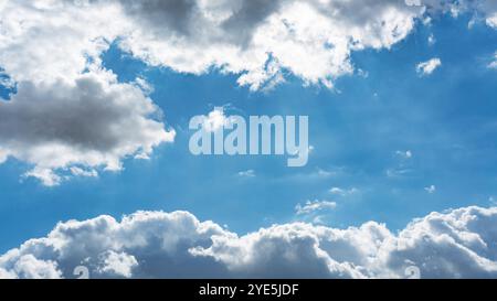 Hintergrund der hinterleuchteten weißen Wolkenkörper von Cumulus, die im klaren blauen Himmel schweben Stockfoto