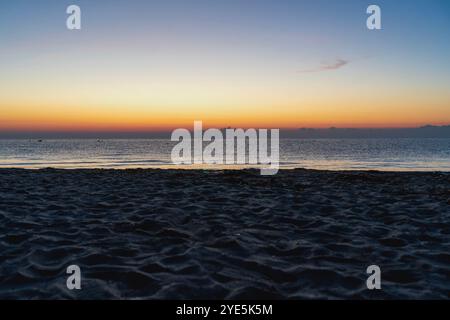 Sonnenaufgang über Sandstrand in der Ägäis – Schönheit außerhalb der Saison in Orange- und Blautönen Stockfoto